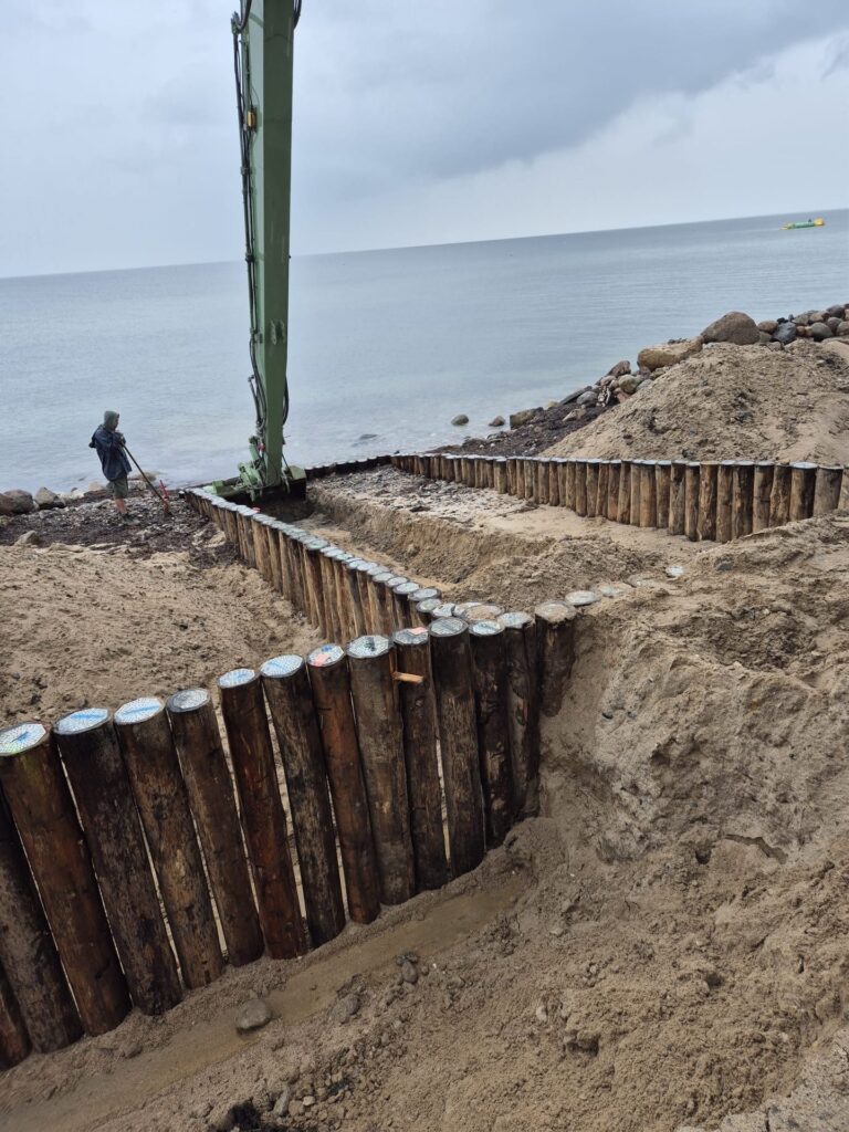Nieuwe beschoeiing van eucalyptus cloeziana palen langs het strand bij Süssau, Duitsland